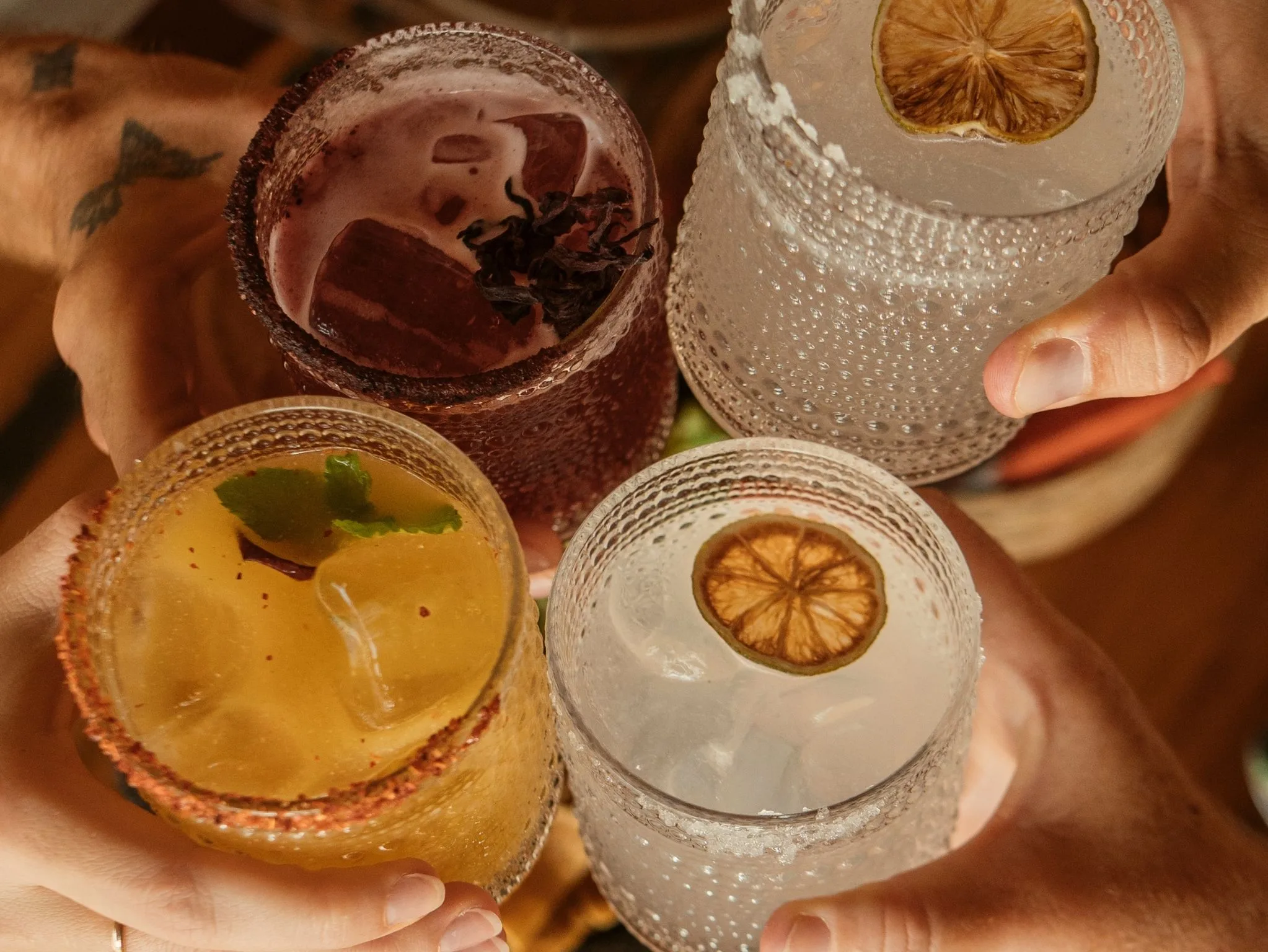 Four Cachasol cocktails raised in a toast, seen from above